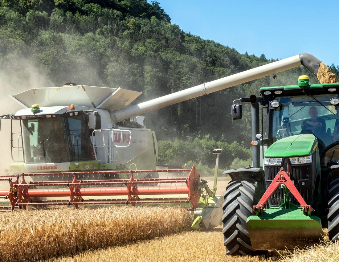 Illustrative stock photo: A combine harvester and a tractor in a wheat field.