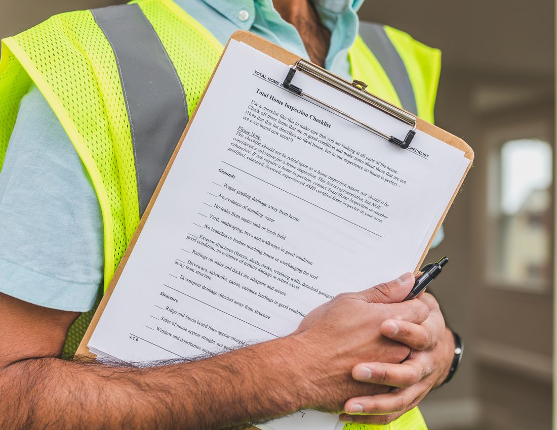 Illustrative stock photo: A person in a reflective vest holding a checklist.