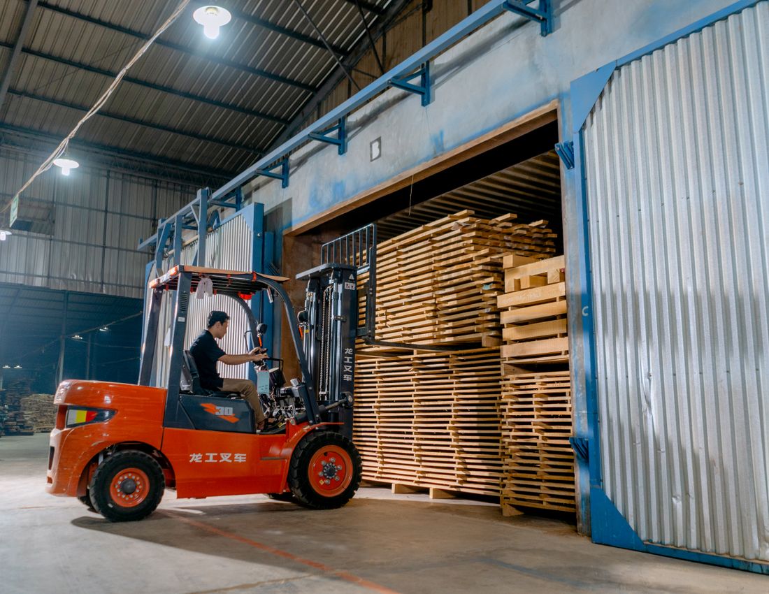 Illustrative stock photo: A forklift among stacks of timber indoors.