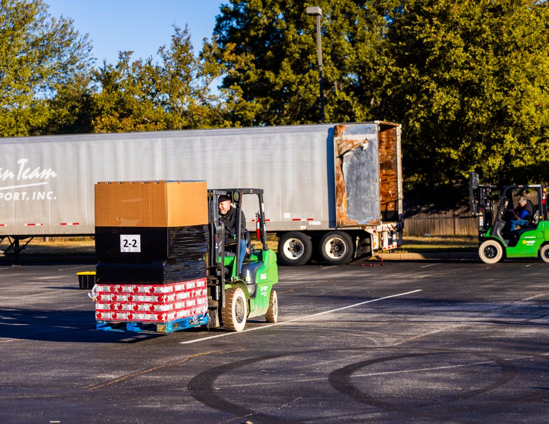 Illustrative stock photo: A forklift loading pallets beside a truck.
